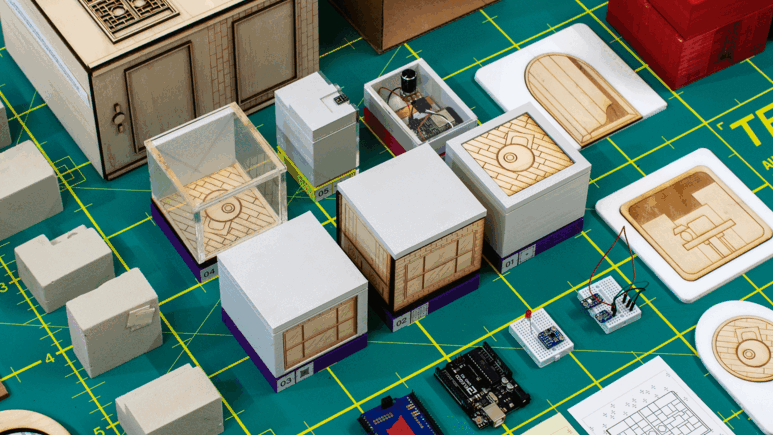 Animated: prototype components laid out on cutting mat — AR content cycling through tool demonstrations